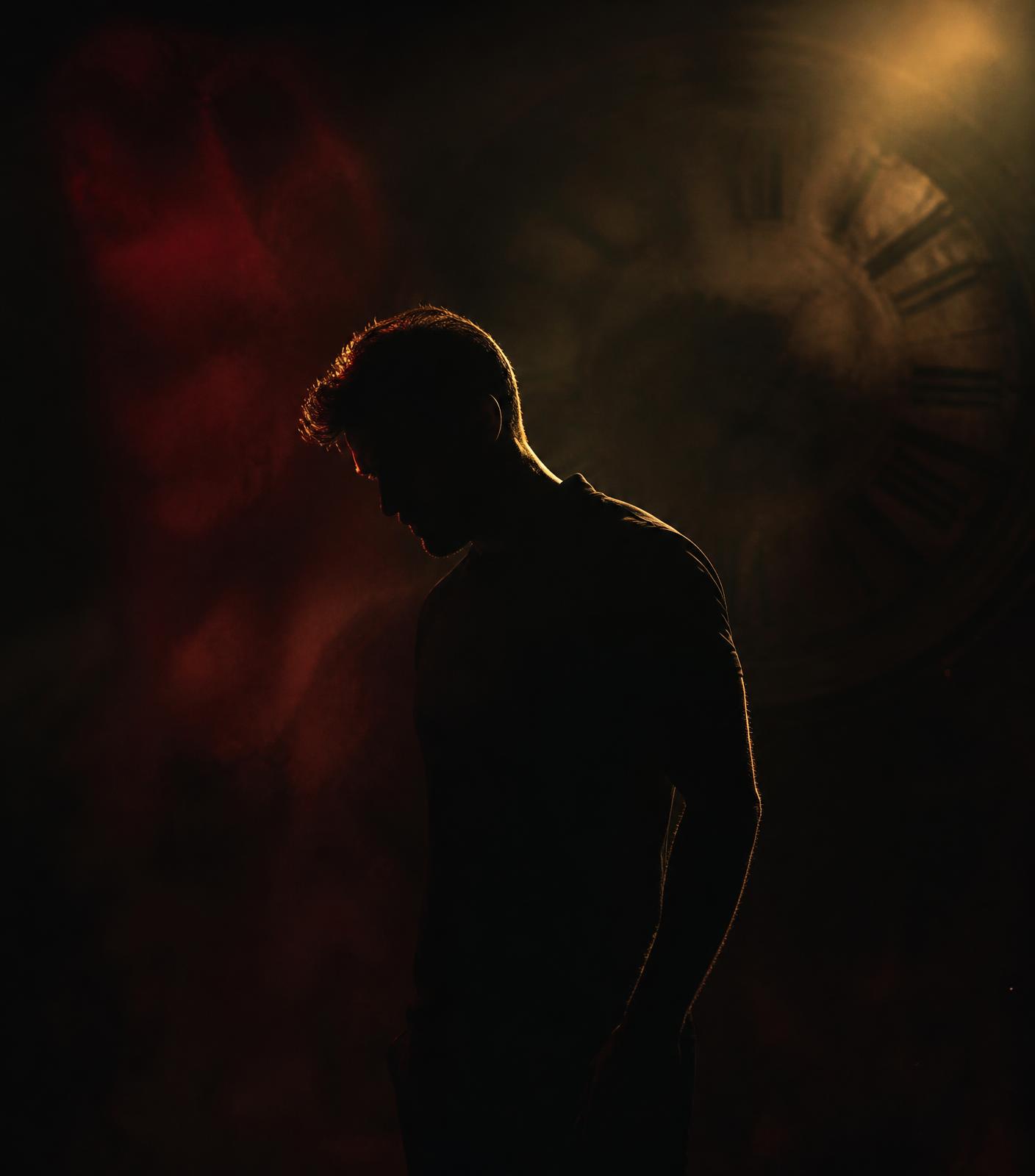 Man in shadow lit by warm light, symbolizing tension and control